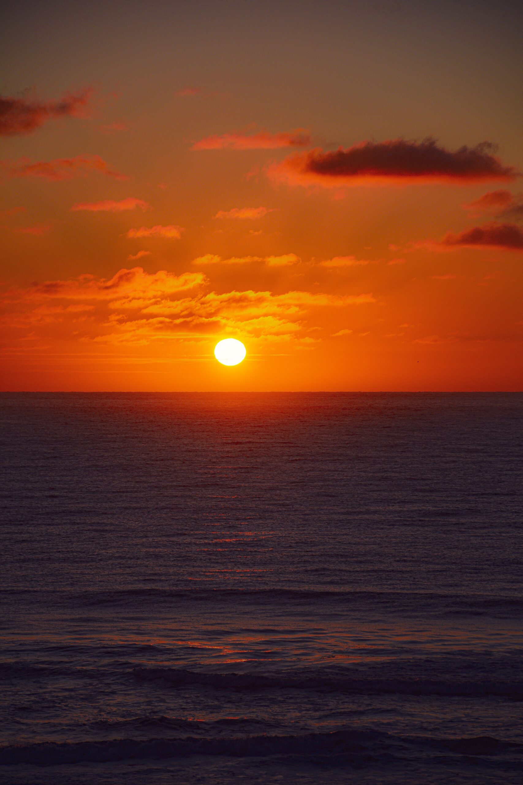 A captivating sunset over the ocean with vibrant orange hues and calm waves.